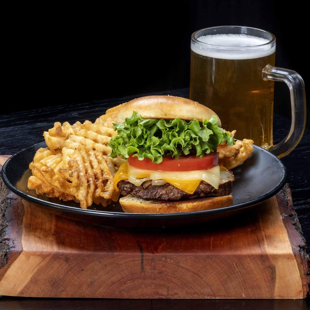 a burger and fries on a plate next to a glass of beer on a wooden surfaceburgers-2