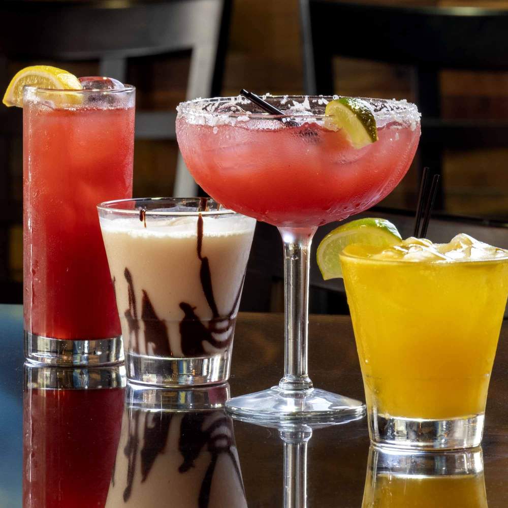 four cocktails shown on a bar